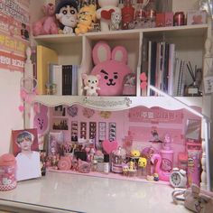 a pink doll house with lots of stuff on the shelves and around it is a teddy bear