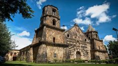 an old church with two towers and a clock on the front is surrounded by green grass