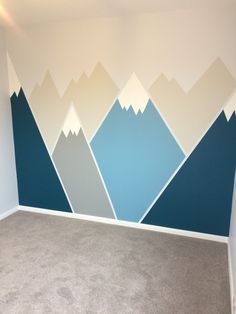 an empty room with mountains painted on the wall and carpeted flooring in front of it