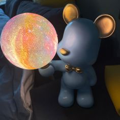 a small blue rat holding a glowing ball in its hand and standing next to it