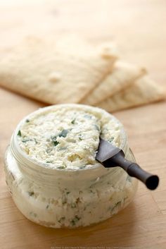 a jar filled with food sitting on top of a wooden table next to crackers