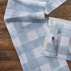 a place setting on a wooden table with napkins and silverware in front of it