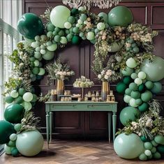 a table topped with green balloons and greenery