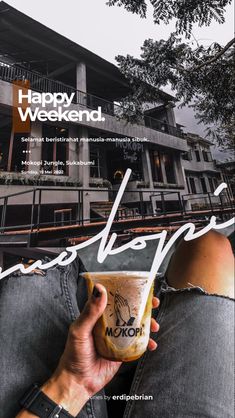 a person holding up a coffee cup in front of a building with the words happy weekend written on it