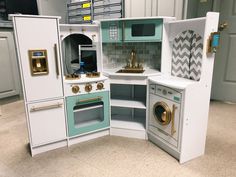 a play kitchen with blue and white cabinets, gold accents, and washer and dryer