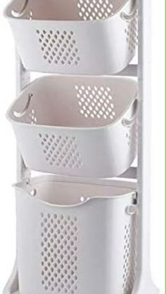 three white baskets are stacked on top of each other in the corner of a rack