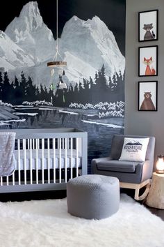 a baby's room decorated in gray and white with mountains painted on the wall