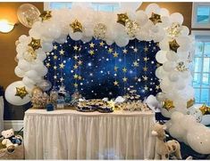 a table topped with balloons and stars under a blue sky filled with gold stars on it