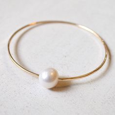 This simple pearl bangle features your choice of a dark grey, white or pale pink freshwater pearl in sterling silver or gold filled. Great for stacking! Made from 14g wire and hammered for a textured look. Pearls are not perfectly round and have some imperfections. They vary in size from 10-12mm. Pearl Bangles Gold, Pearl Bangle Bracelet, Puka Shell Necklace, Shell Choker, Single Pearl, Simple Pearl, Gold Pendant Jewelry, Pearl Bangle, Gold Heart Necklace