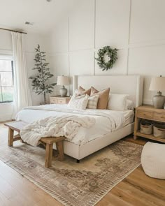 a large white bed sitting in a bedroom on top of a hard wood flooring