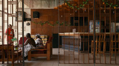 two people sitting at a table in a restaurant with wooden chairs and shelves on the wall