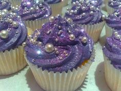 purple cupcakes with blue frosting and sprinkles sitting on top of each other