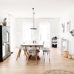 the dining room table is surrounded by white chairs and wood flooring, along with an area rug on the hardwood floor