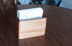 a wooden box with some tissues in it on a table next to a potted plant