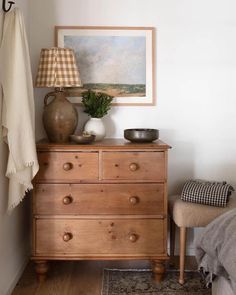 a wooden dresser sitting in a bedroom next to a lamp