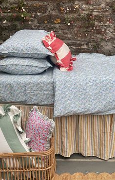 a bed sitting next to a brick wall with pillows on it and a wicker basket