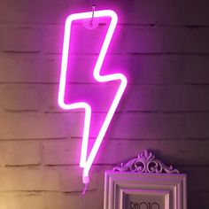 a purple neon sign hanging from the side of a wall next to a white mirror