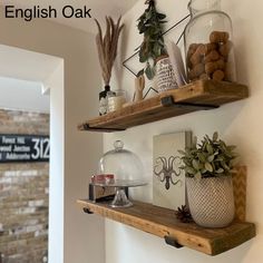 two wooden shelves with pots and plants on them next to a brick wall in a room