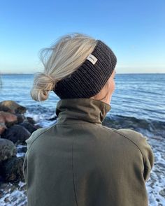 a woman with blonde hair wearing a beanie looking out at the ocean