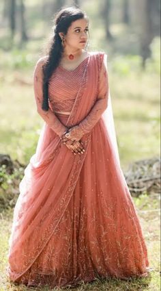 a woman in an orange dress standing in the grass with her hands on her hips