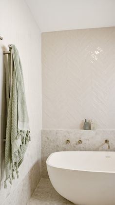 a white bath tub sitting next to a wall mounted towel dispenser in a bathroom