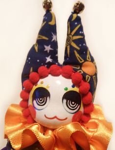 a doll with red hair wearing a blue and orange outfit on it's head