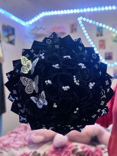 a person holding up a bunch of hair clips in front of a bed with butterflies on it