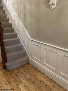 an empty room with wooden floors and white walls, along with a staircase leading up to the second floor