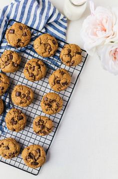 chocolate chip cookies cooling on a wire rack next to a glass of milk and flowers