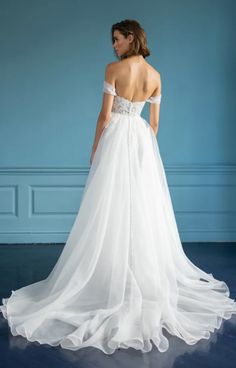 a woman in a white wedding dress looking off to the side with her back turned