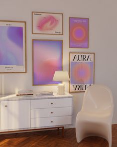 a white chair sitting next to a table with a lamp on it in front of pictures