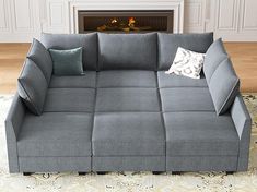 a gray couch sitting on top of a rug next to a fire place in a living room