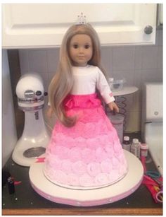 a doll is sitting on top of a cake