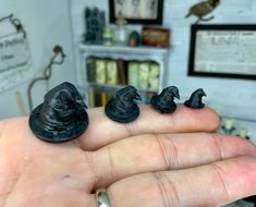 three miniature witches sitting on the palm of someone's hand in front of a bookshelf