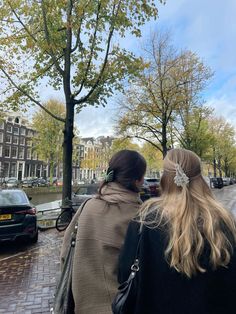 two women are walking down the street with their backs to each other and one is wearing a scarf