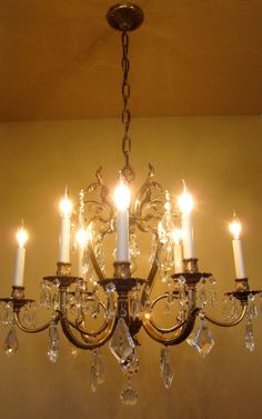 a chandelier hanging from the ceiling with many candles lit up in front of it