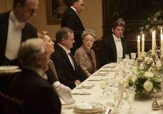 a group of people sitting around a dinner table with candles on top of the tables