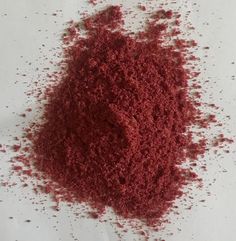 a pile of red sand sitting on top of a white table