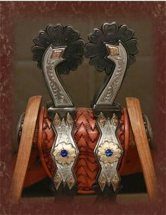 two silver and brown horse stirs sitting on top of a wooden stand with blue stones