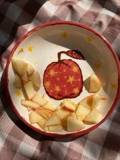 a bowl filled with cut up apples on top of a checkered tablecloth covered table