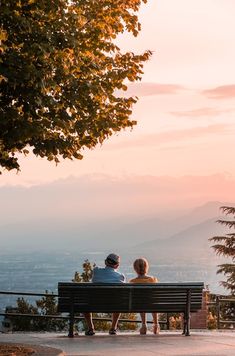 two people sitting on a bench looking at the view