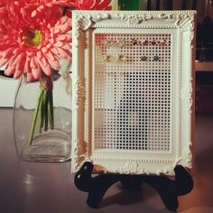 there is a vase with pink flowers in it and a white frame on the table