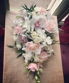 a bouquet of white and pink flowers sitting on top of a table next to a window