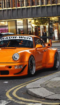 an orange sports car driving down the street