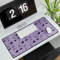 a computer desk with a purple mouse pad and keyboard on it, next to a plant