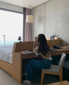 a woman sitting at a desk in front of a window looking out onto the ocean