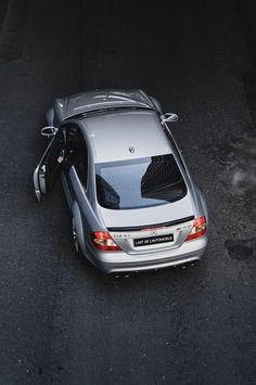 a silver car is parked on the side of the road with it's door open