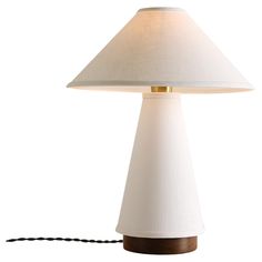 a table lamp with a white shade on it and a black cord attached to the base