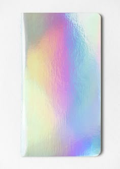 a square metallic notebook cover on a white surface with an iridescent pattern in the middle