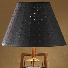 a table lamp with a black shade on it's side and a wooden base